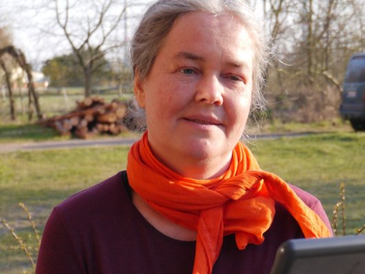 Anke Dübler sitz im Freien vor ihrem Tablet in einer Online-Konferenz.